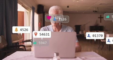 Senior man typing on laptop, generating social media alerts rising and eliciting greeting wave - Powered by Adobe