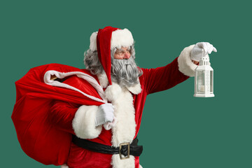 Santa Claus with bag of Christmas gifts and lantern on green background