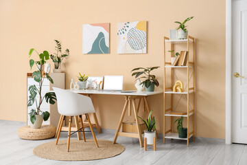 Interior of stylish office with workplace, bookshelf and houseplants