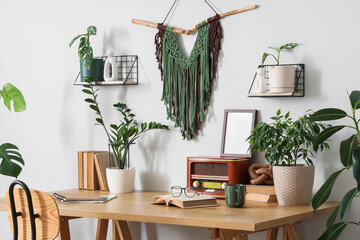 Interior of light office with workplace, books and houseplants