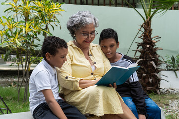 Grandmother reading book to grandchildren in garden
