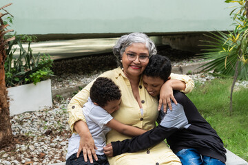 Fototapeta premium Grandmother embracing grandchildren outdoors demonstrating family love