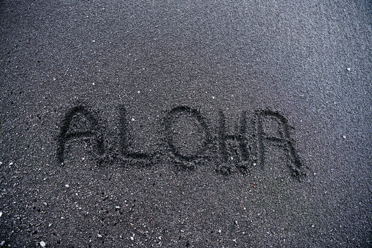 Word “Aloha” and a heart drawn in the unique green sand at Papakōlea Green Sand Beach, Big Island, Hawaii.