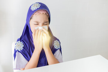 Muslim girl in hijab blowing nose with tissue, suffering from cold or flu symptoms. Healthcare and illness concept with white background.tuberculosis protection, she use tissue paper close mouth.