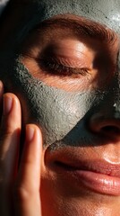 Fototapeta premium Woman smiling with clay face mask in warm sunlight