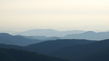 Obraz premium Serene mountain landscape with layers of misty blue peaks under a pale sky