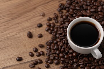 Obraz premium White cup full of coffee sits on a wooden table surrounded by roasted coffee beans, creating a cozy and aromatic scene