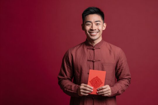 Male coworker in mandarin-collar shirt holding a red envelope, celebrating Lunar New Year.