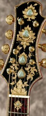 Ornate guitar headstock with gold inlay and light-green gemstones