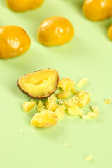 Fresh Raw Chestnuts with Cracked Shell Revealing Golden Kernels on Green Background