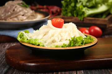 Hot tripe dish with fresh vegetables and tomato garnish on rustic wooden serving board