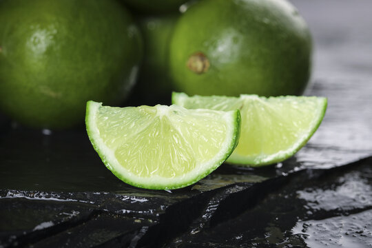 Fresh Green Lime Wedges on Dark Slate - Studio Shot of Juicy Citrus Fruit