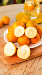 Fresh Kumquats Whole and Sliced on Wooden Cutting Board with Glass Jar
