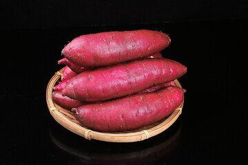 Fresh Sweet Potatoes in Wicker Basket on Black Background