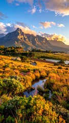 A scenic vista of rolling hills, tranquil stream, and majestic mountains bathed in warm golden light at sunset.