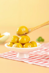 Glazed Chestnuts in Syrup on White Plate with Wooden Spoon - Sweet Preserved Nuts