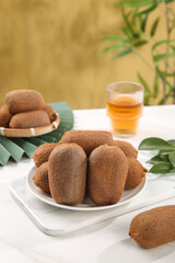 Fresh Kiwifruit Display with Tea Glass and Green Leaves on White Table