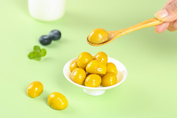 Fresh Golden Chestnuts in Syrup with Wooden Spoon on Green Background