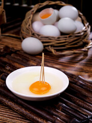 Fresh Farm Eggs in Basket with Raw Egg Yolk on Rustic Wood - Free Range Organic Cooking Ingredients