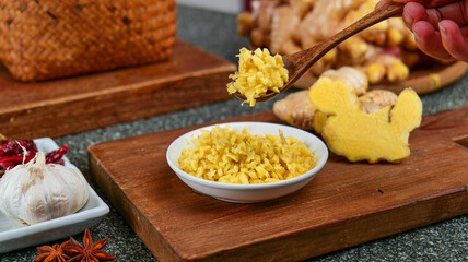 Fresh Grated Ginger Root with Wooden Spoon and Cooking Ingredients on Rustic Cutting Board