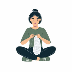 Woman sits cross-legged, happily knitting a light-colored garment.