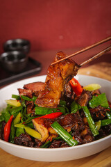 Hand-shredded smoked duck with vegetables held by chopsticks, preserved Asian food dish ready for sharing
