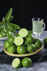 Fresh Green Limes in Bamboo Basket with Lime Juice Glass on Dark Wood Background - Studio Food Photography