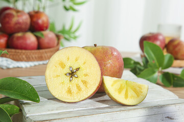 Fresh Sliced Apples on Rustic White Wooden Table with Fruit Baskets and Green Leaves