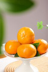 Fresh Sweet Persimmons from Fuping Shaanxi China on White Plate with Green Leaves