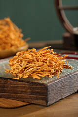 Dried Yunnan Cordyceps Traditional Chinese Herbs on Wooden Surface with Antique Scale