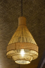A beautifully crafted, handmade bamboo or rattan pendant lamp hangs from the ceiling, its warm, glowing light creating a cozy and inviting atmosphere. 