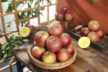 Fresh Picked Apples in Wicker Basket on Rustic Wooden Table with Garden Background