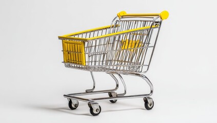 A small, empty, chrome shopping cart with bright yellow accents sits on a plain white background. Its miniature size and clean lines suggest a conceptual image related to consumerism or retail
