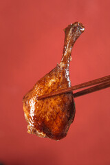 Cantonese Style Roasted Duck Leg with Chopsticks on Red Background - Traditional Asian Cuisine