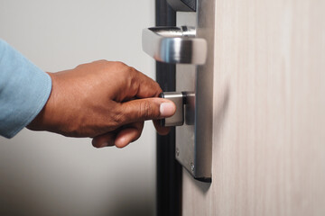Hand opening a modern door lock at a hotel room