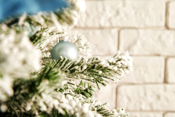 Nice blue festive ball on the green Christmas tree branch with bricks on the back. Soft bright image. Holidays backgrounds with copy space