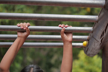 Child practicing on monkey bars in a park