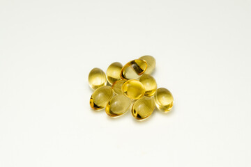 golden softgel capsules on white background, vitamins or omega 3 supplements