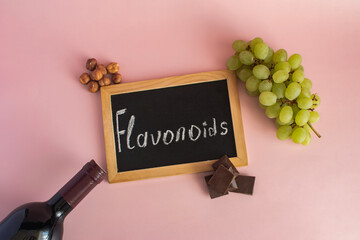 Products containing flavonoids in their composition. Grapes, onions, garlic, chocolate, tea close-up on a light background and the inscription flavonoids on a dark board