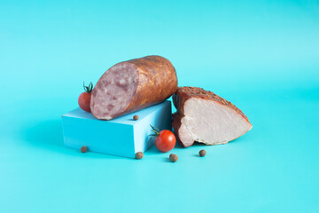 Various types of sausages and meat products in a package, sliced sausage and cherry tomatoes in close-up on a light background