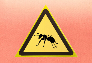 The warning sign is a silhouette of an ant insect in a yellow triangle on a light background. The "Attention, ants" sign is a close-up yellow triangle.