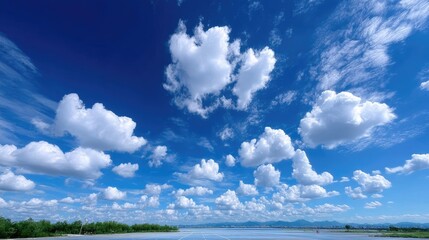 Bright Blue Sky Dominated by Fluffy White Clouds on a Sunny Day with Soft Atmosphere Above a Distant Horizon