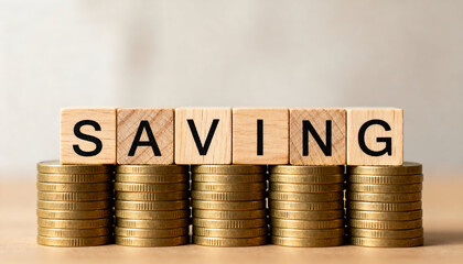 SAVING text displayed on wooden blocks placed over stacked gold coins