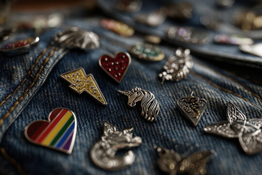 Colorful collection of pride-themed enamel pins on denim jacket