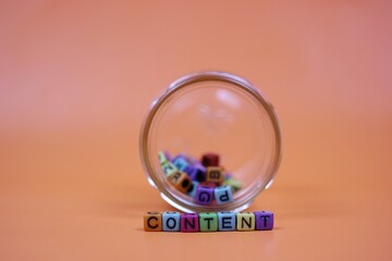Colorful Blocks Spelling 'Content' Spilling Out of a Glass Jar. symbolizing creativity and content creation. with an orange background
