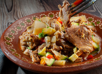 Chicken stew with vegetables such as potatoes, zucchini, carrots, and a fork holding a piece of chicken, viewed from a side angle on a rustic wooden table. Macro photography.