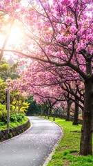 Obraz premium A winding paved road adorned with vibrant pink flowers lining the edges, creating a picturesque scene under a clear blue sky.