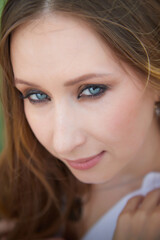 Woman with striking blue eyes enjoying a sunny day outdoors in a lush green environment