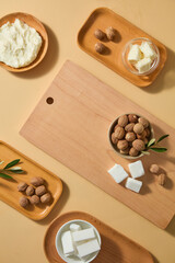Neat flat lay of raw shea butter cubes in wooden bowl, scattered shea nuts and soft leaves on pale surface, perfect for skincare branding or DIY tutorials. Space to place your product