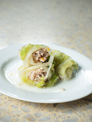 sukiyaki roll, stuffed pork in lettuce wrap, on white dish